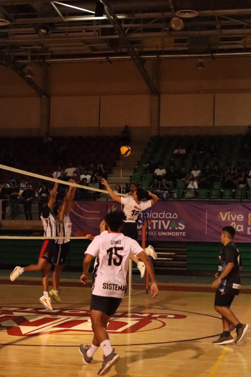 Andrés spiking the ball over the net during a university volleyball match
